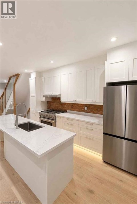 A modern kitchen with white cabinets and a stainless steel refrigerator.