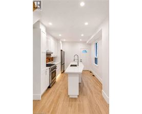 A modern kitchen with white cabinets and a wooden floor.