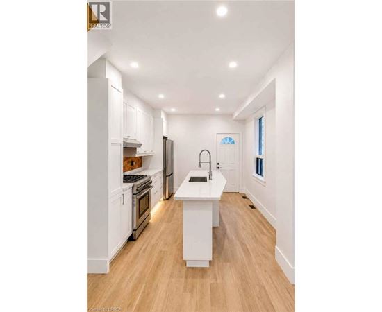 A modern kitchen with white cabinets and a wooden floor.