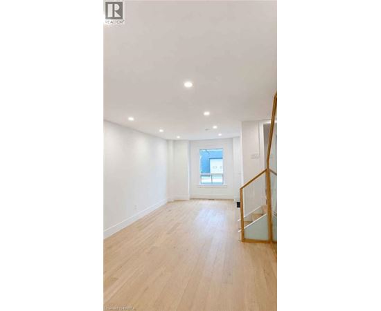 A spacious room with wooden flooring and a window.