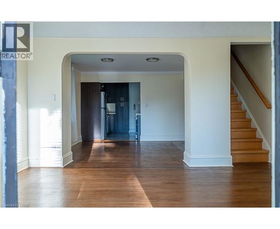 A spacious hallway with a staircase on the right and a doorway leading to another room on the left.