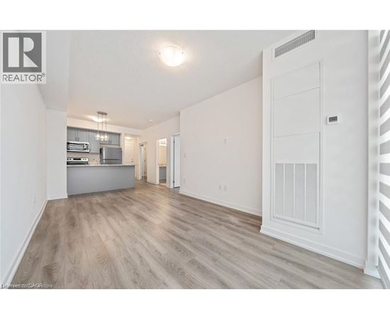 A spacious, empty room with light wood flooring and white walls.