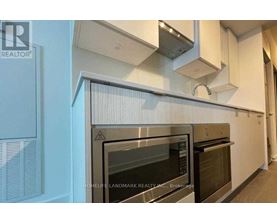 A modern kitchen with a stainless steel oven and white cabinets.