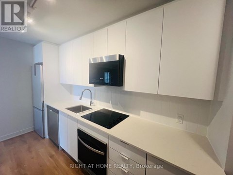 A kitchen with white cabinets and a black countertop.
