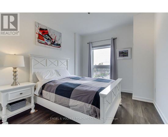 A bedroom with a large bed and a nightstand with a lamp.
