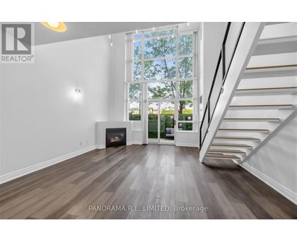 A spacious living room with wood flooring and a staircase leading to the upper level.