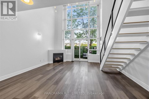 A spacious living room with wood flooring and a staircase leading to the upper level.