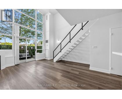 A spacious room with a staircase leading to the upper floor.