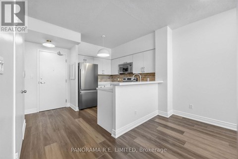 A kitchen with white cabinets and a wooden floor.