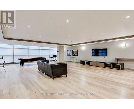 A spacious living room with a dark brown sofa and a television mounted on the wall.