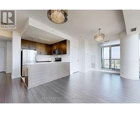 A spacious living room with a kitchen in the background.