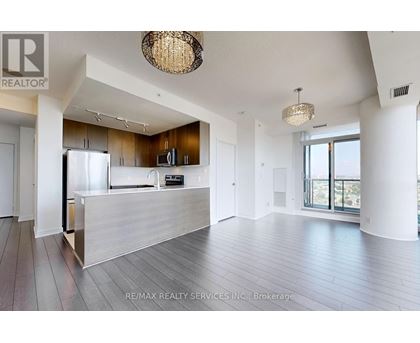 A spacious living room with a kitchen in the background.
