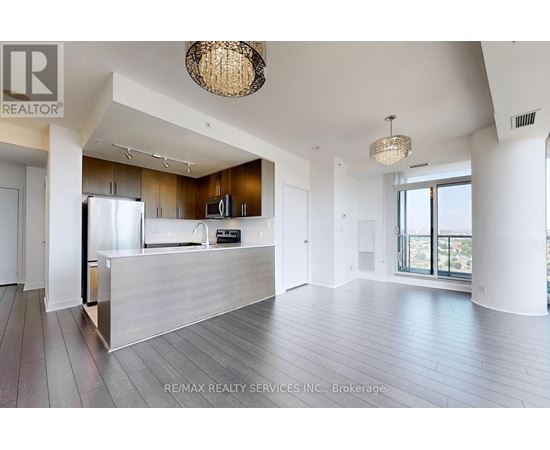 A spacious living room with a kitchen in the background.