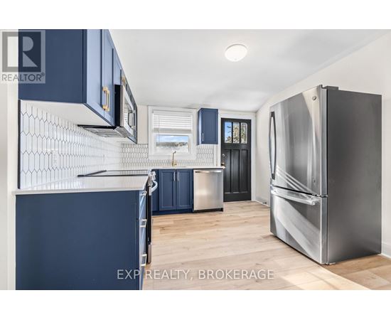 A kitchen with dark blue cabinets and a stainless steel refrigerator.