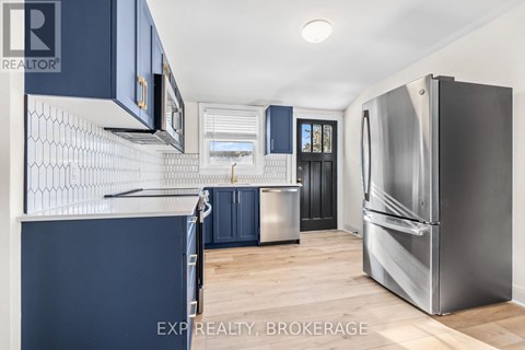 A kitchen with dark blue cabinets and a stainless steel refrigerator.
