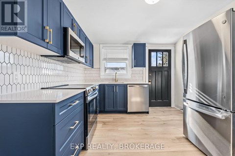 A kitchen with blue cabinets and a stainless steel refrigerator.
