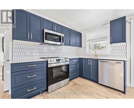 A kitchen with dark blue cabinets and a white tiled backsplash.