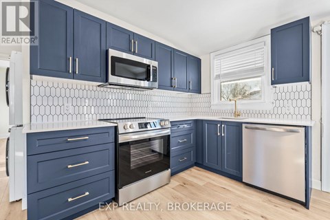 A kitchen with dark blue cabinets and a white tiled backsplash.
