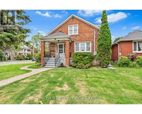 A red brick house with a front porch and a tree in front.