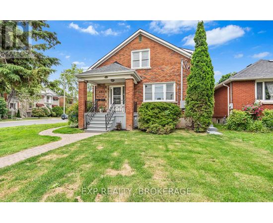 A red brick house with a front porch and a tree in front.