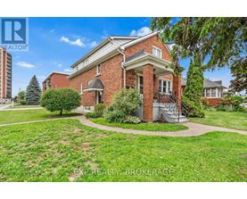 A red brick house with a tree in front of it.