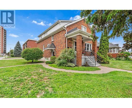 A red brick house with a tree in front of it.