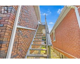 A wooden staircase leads up to a balcony on a brick building.