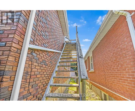 A wooden staircase leads up to a balcony on a brick building.