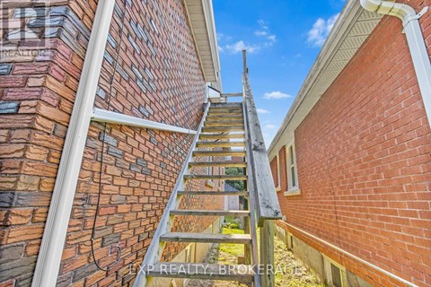 A wooden staircase leads up to a balcony on a brick building.