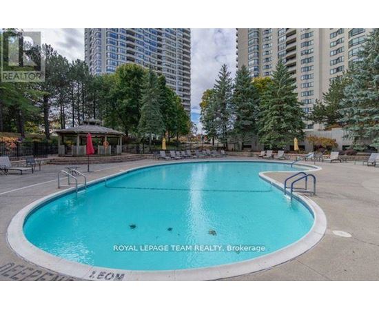 A pool surrounded by trees and apartment buildings.
