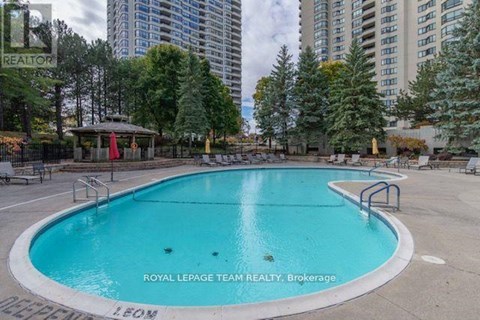 A pool surrounded by trees and apartment buildings.