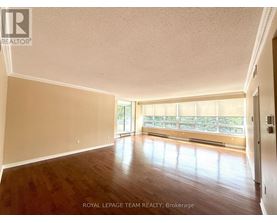 A spacious room with wooden floors and a large window.
