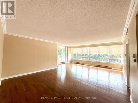 A spacious room with wooden floors and a large window.