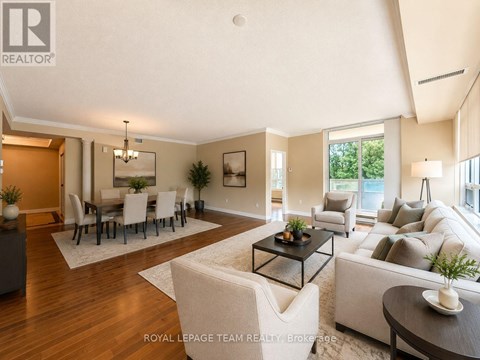 A well-lit, spacious living room with a dining area in the background.