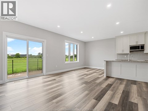 A spacious room with wooden flooring and white walls.
