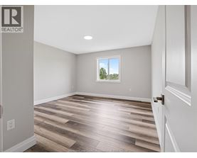 A room with wooden flooring and a window showing trees outside.
