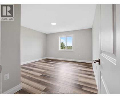 A room with wooden flooring and a window showing trees outside.