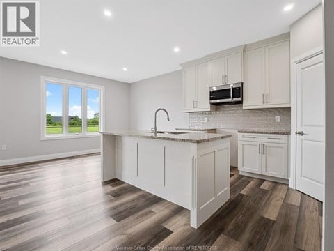 A kitchen with white cabinets and a wooden floor.