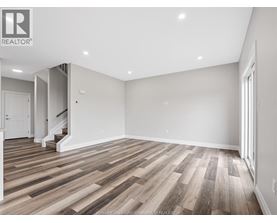 A spacious room with wooden flooring and white walls.