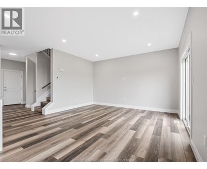 A spacious room with wooden flooring and white walls.