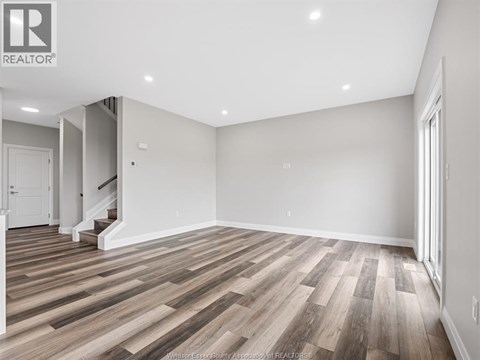 A spacious room with wooden flooring and white walls.