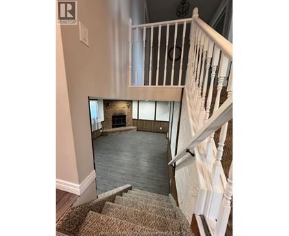A staircase with a carpeted runner leads to a living room with a fireplace.