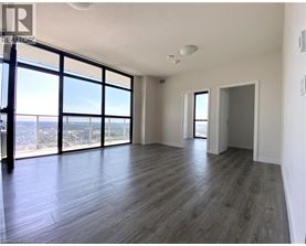 A spacious room with wooden flooring and large windows overlooking the city.