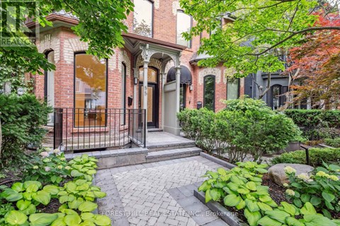 A brick house with a black gate and a small garden in front.
