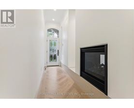 A hallway with a wood floor and a glass door leading to a balcony.