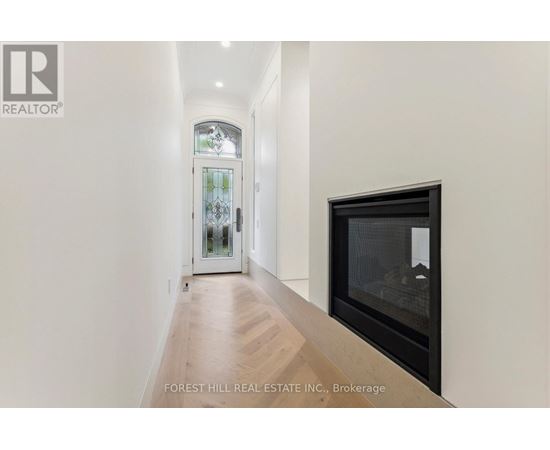 A hallway with a wood floor and a glass door leading to a balcony.
