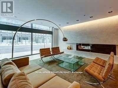 A modern living room with a glass table and leather chairs.