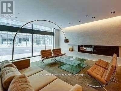 A modern living room with a glass table and leather chairs.