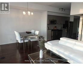 A modern kitchen and dining area with white furniture and a glass table.