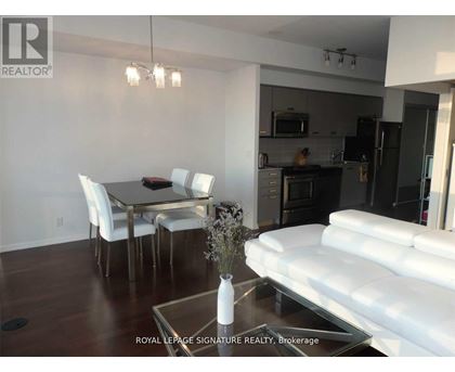 A modern kitchen and dining area with white furniture and a glass table.